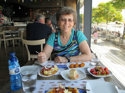 Photo shows Dona sitting at the same table with about 5 small plates of food.